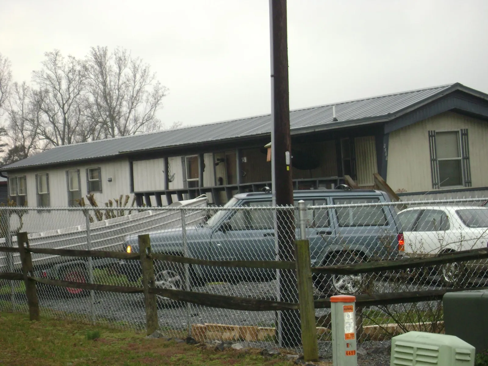Dark metal roof on a long single story building behind a chain link fence in Alamo